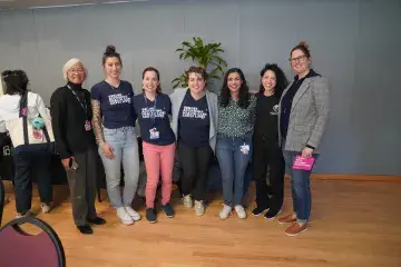 7 individuals in with arms around each other smile for a photo at a gender-affirming care presentation.