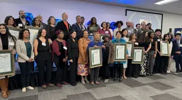 20+ awardees of Mia Bonta's award stand with their framed resolutions.