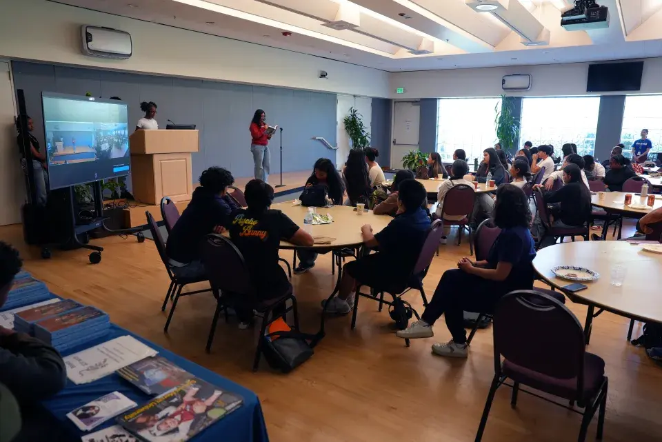 Students gather at round tables to engage in reading session.